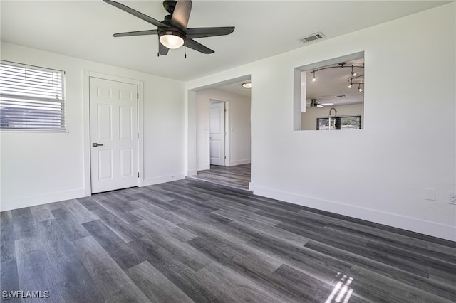 unfurnished room with dark wood-style floors, visible vents, baseboards, ceiling fan, and rail lighting