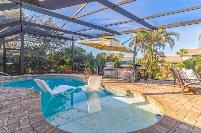 view of swimming pool featuring exterior bar, a grill, exterior kitchen, a lanai, and a patio area