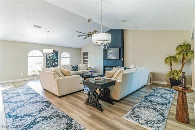 living room with hardwood / wood-style flooring, lofted ceiling, and ceiling fan with notable chandelier