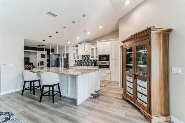 kitchen featuring sink, white cabinetry, light stone counters, pendant lighting, and black appliances