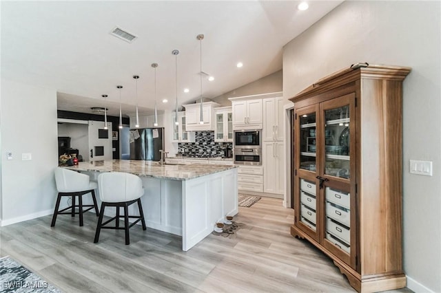 kitchen featuring visible vents, a sink, stainless steel appliances, white cabinets, and light wood-type flooring