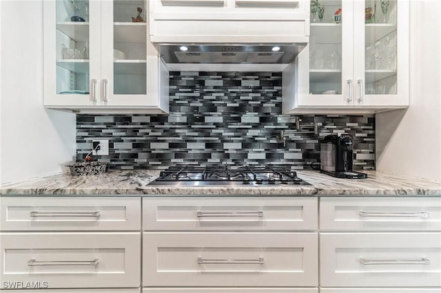 kitchen with light stone countertops, stainless steel gas cooktop, decorative backsplash, and white cabinets