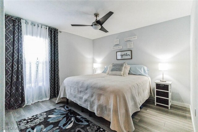 bedroom with wood finished floors, baseboards, and ceiling fan