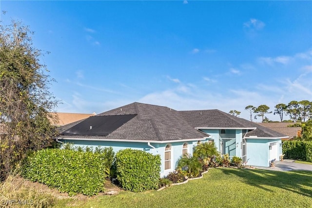 view of front of home featuring stucco siding, a front lawn, and roof with shingles