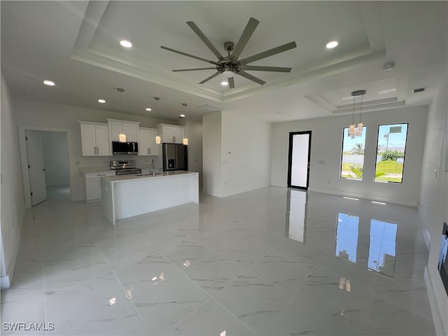 kitchen featuring appliances with stainless steel finishes, ceiling fan with notable chandelier, a tray ceiling, and white cabinets