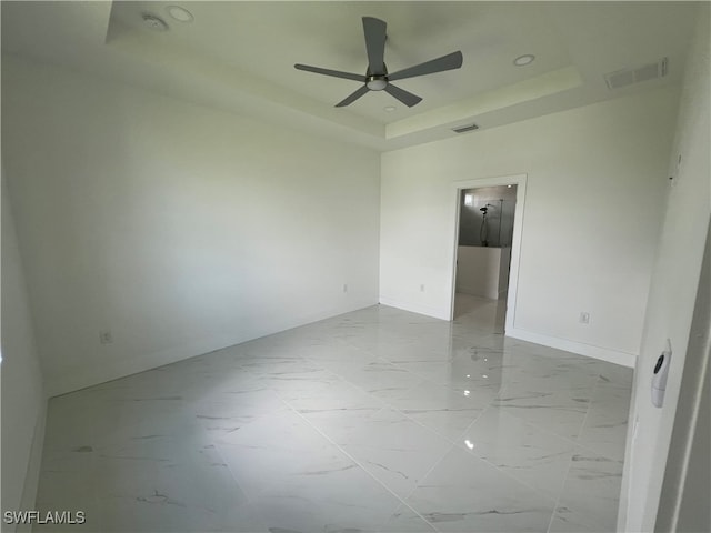 unfurnished room featuring ceiling fan and a tray ceiling