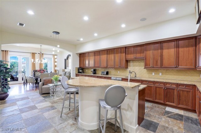 16649 Toscana Cir Unit 803, Naples, FL 34110 - kitchen with a chandelier, tasteful backsplash, arched walkways, light stone counters, and a breakfast bar area