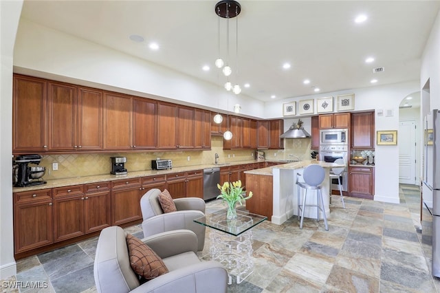 16649 Toscana Cir Unit 803, Naples, FL 34110 - kitchen featuring pendant lighting, a breakfast bar area, appliances with stainless steel finishes, a center island with sink, and arched walkways