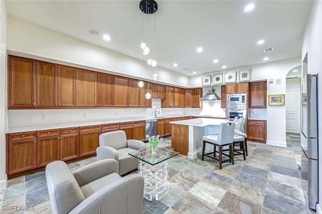 16649 Toscana Cir Unit 803, Naples, FL 34110 - kitchen with appliances with stainless steel finishes, a kitchen bar, light countertops, brown cabinets, and a kitchen island