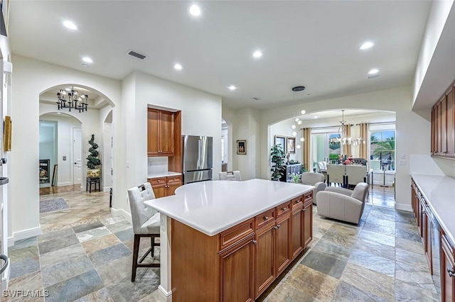 16649 Toscana Cir Unit 803, Naples, FL 34110 - kitchen with freestanding refrigerator, stone tile floors, a chandelier, recessed lighting, and arched walkways