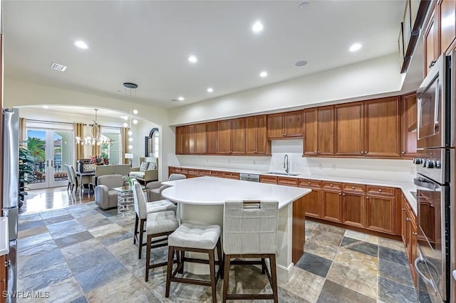 16649 Toscana Cir Unit 803, Naples, FL 34110 - kitchen with arched walkways, appliances with stainless steel finishes, light countertops, a breakfast bar, and a chandelier