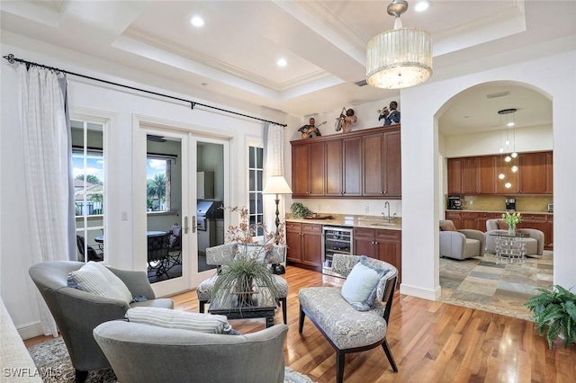 16649 Toscana Cir Unit 803, Naples, FL 34110 - living room with wine cooler, bar with sink, arched walkways, light wood-style flooring, and crown molding