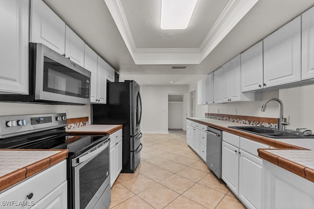 kitchen featuring a raised ceiling, white cabinetry, sink, tile counters, and stainless steel appliances