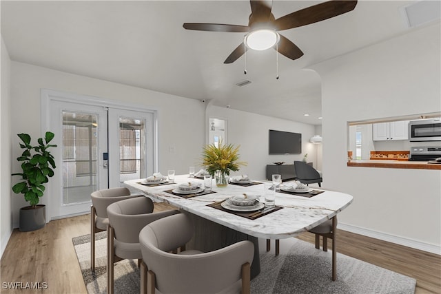 dining area featuring lofted ceiling, french doors, and light wood-type flooring