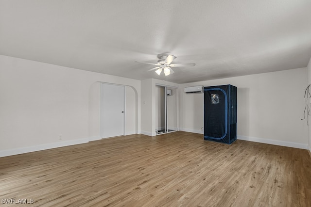 unfurnished room with ceiling fan, an AC wall unit, and light hardwood / wood-style floors