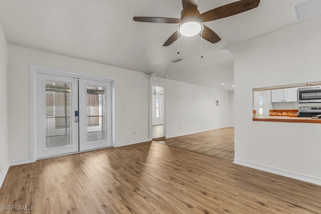 unfurnished living room with french doors, ceiling fan, vaulted ceiling, and light hardwood / wood-style flooring