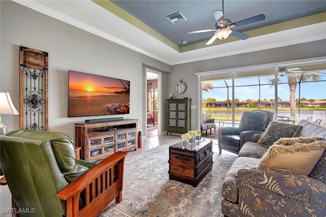 tiled living room featuring a raised ceiling, ceiling fan, and crown molding