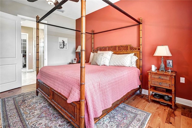 bedroom with ceiling fan, wood-type flooring, and a spacious closet