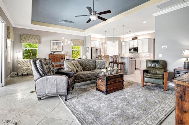 tiled living room featuring a tray ceiling, ceiling fan, and a healthy amount of sunlight