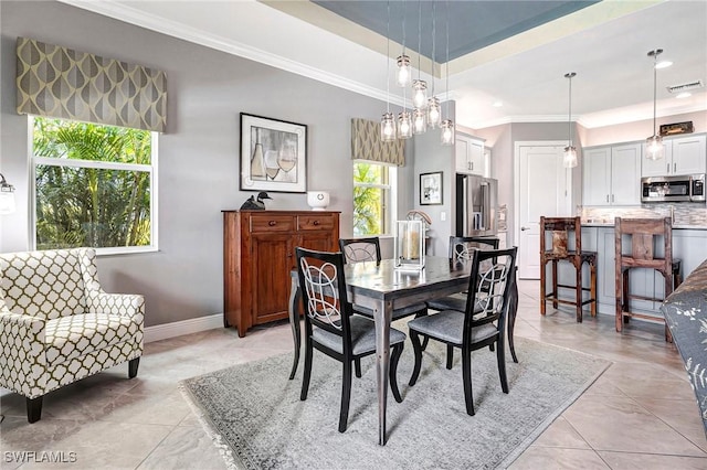 dining space featuring light tile patterned floors, a tray ceiling, and crown molding