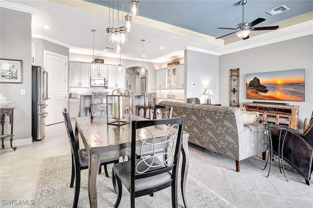 tiled dining area with a tray ceiling, ceiling fan, and crown molding