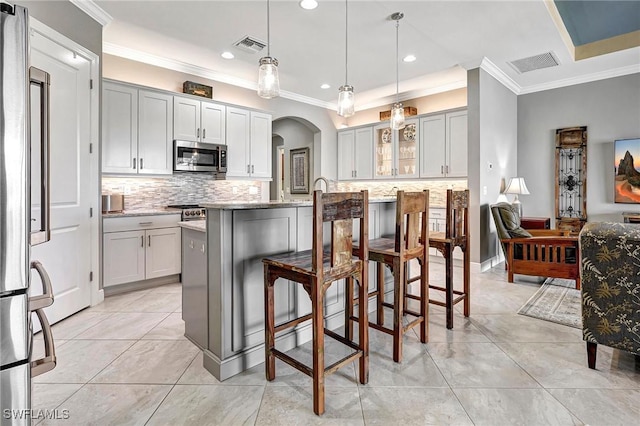 kitchen with a kitchen breakfast bar, pendant lighting, a center island with sink, and stainless steel appliances