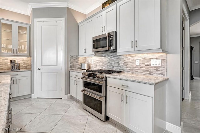 kitchen featuring light stone counters, white cabinetry, backsplash, and appliances with stainless steel finishes