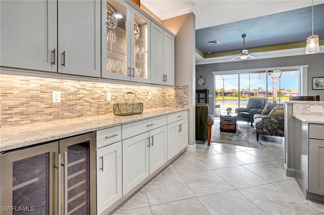 kitchen with pendant lighting, wine cooler, decorative backsplash, ceiling fan, and light stone countertops