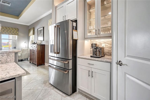 kitchen with stainless steel fridge, tasteful backsplash, white cabinetry, and light stone counters