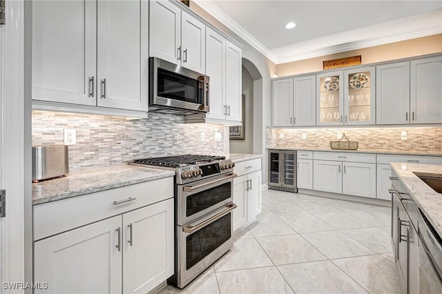 kitchen featuring wine cooler, ornamental molding, tasteful backsplash, light stone counters, and stainless steel appliances