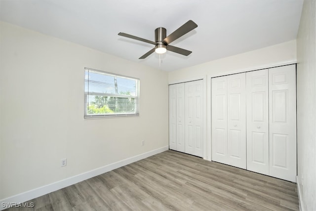 unfurnished bedroom featuring multiple closets, light hardwood / wood-style flooring, and ceiling fan