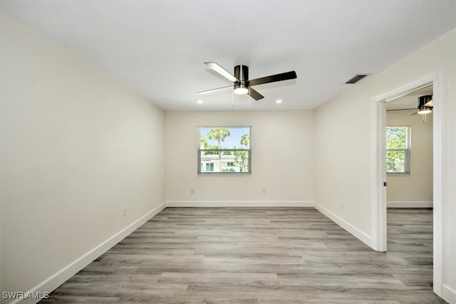 empty room featuring a healthy amount of sunlight, ceiling fan, and light hardwood / wood-style flooring