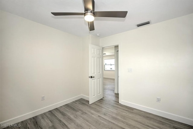 empty room with visible vents, baseboards, wood finished floors, and a ceiling fan