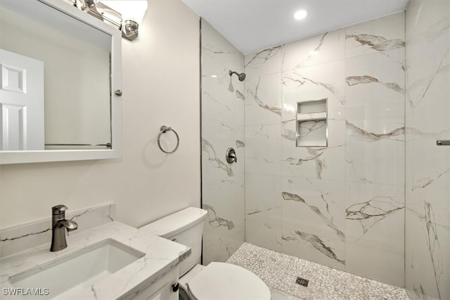 bathroom with vanity, toilet, and a tile shower