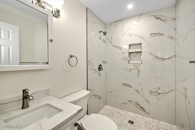 bathroom featuring a marble finish shower, toilet, and vanity