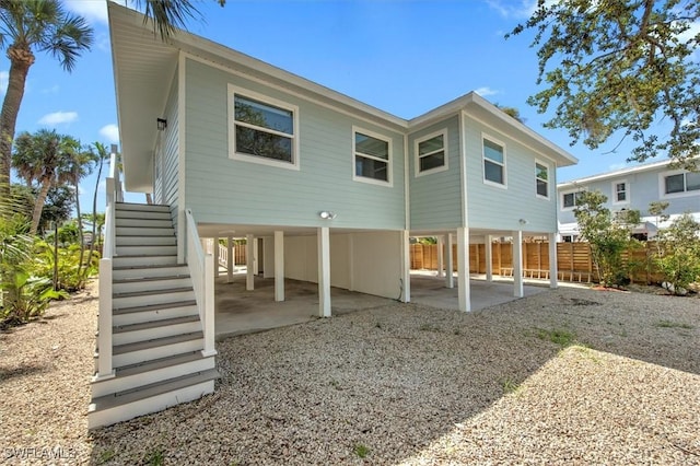 rear view of house with gravel driveway, a carport, and a patio