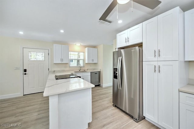 kitchen with a sink, visible vents, appliances with stainless steel finishes, and white cabinets