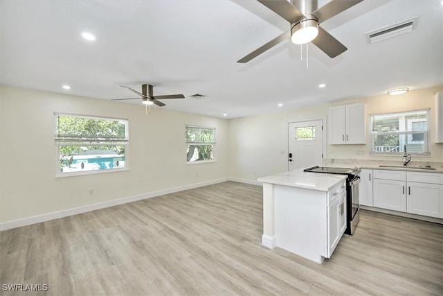 kitchen with white cabinets, plenty of natural light, stainless steel electric range, and ceiling fan