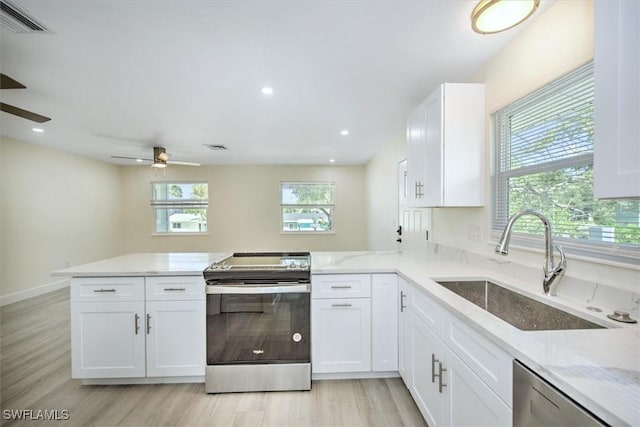 kitchen with a sink, white cabinetry, stainless steel appliances, a peninsula, and light stone countertops