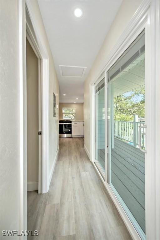 hallway with attic access, baseboards, and light wood finished floors