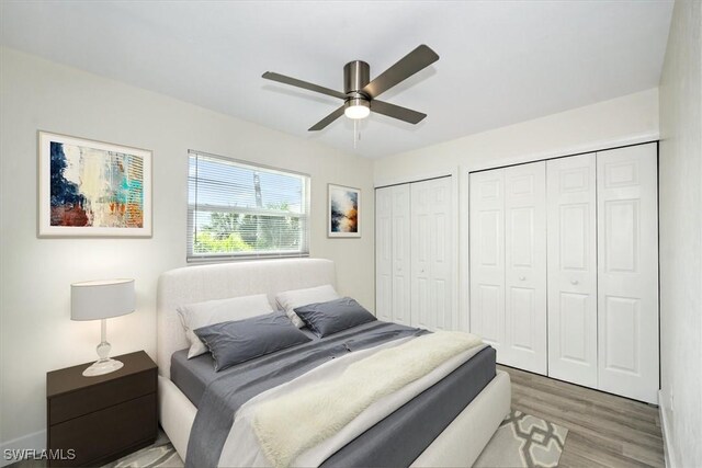 bedroom featuring ceiling fan, two closets, and hardwood / wood-style flooring