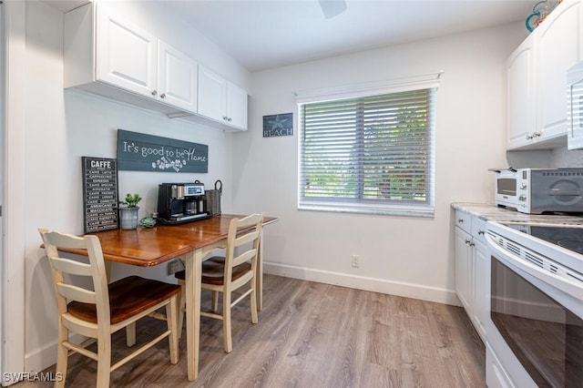 dining space with light wood-style floors, baseboards, and a toaster