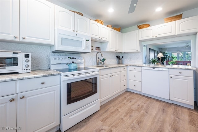 kitchen with white cabinetry, tasteful backsplash, light wood-type flooring, white appliances, and a sink