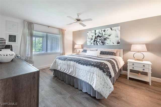 bedroom featuring baseboards, wood finished floors, and a ceiling fan