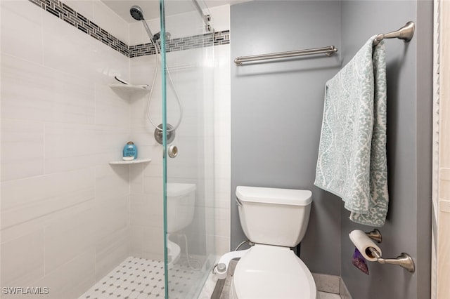 bathroom featuring a shower with door and toilet