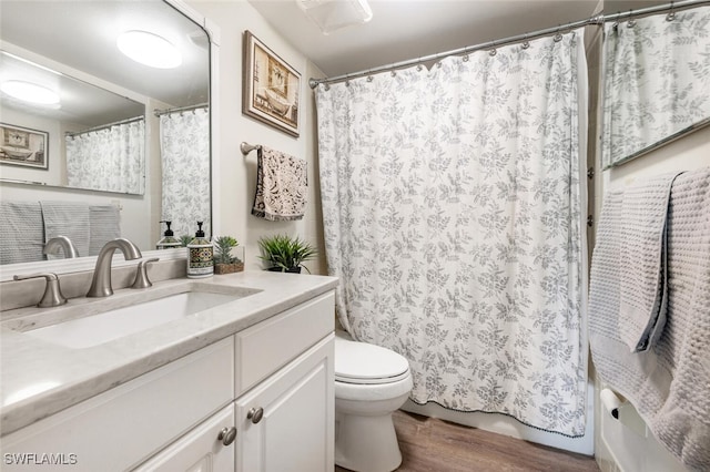 full bath with toilet, vanity, and wood finished floors