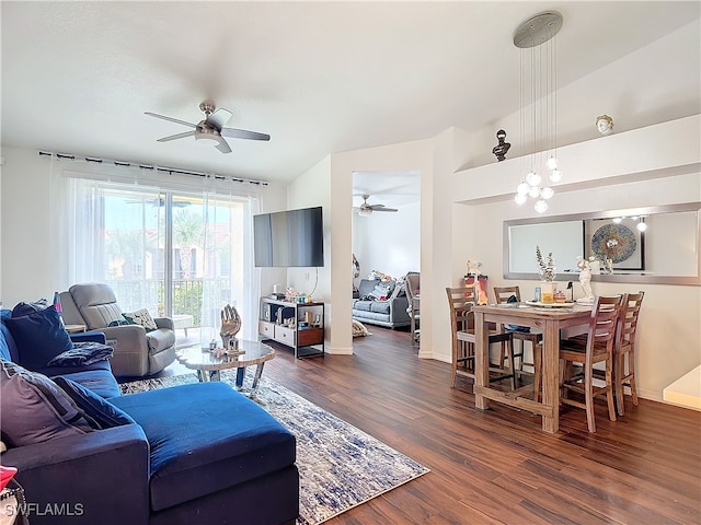 living room with lofted ceiling, dark wood-type flooring, and ceiling fan with notable chandelier