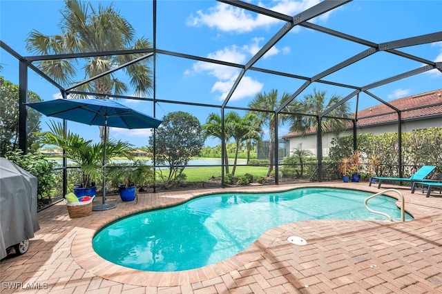 pool with a patio area, glass enclosure, and area for grilling