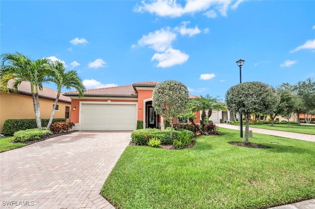 view of front facade with a garage, a tiled roof, decorative driveway, a front lawn, and stucco siding