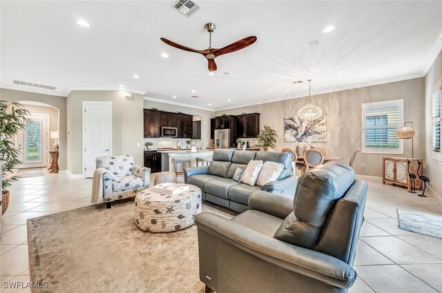 living room featuring ornamental molding, ceiling fan with notable chandelier, and light tile patterned floors